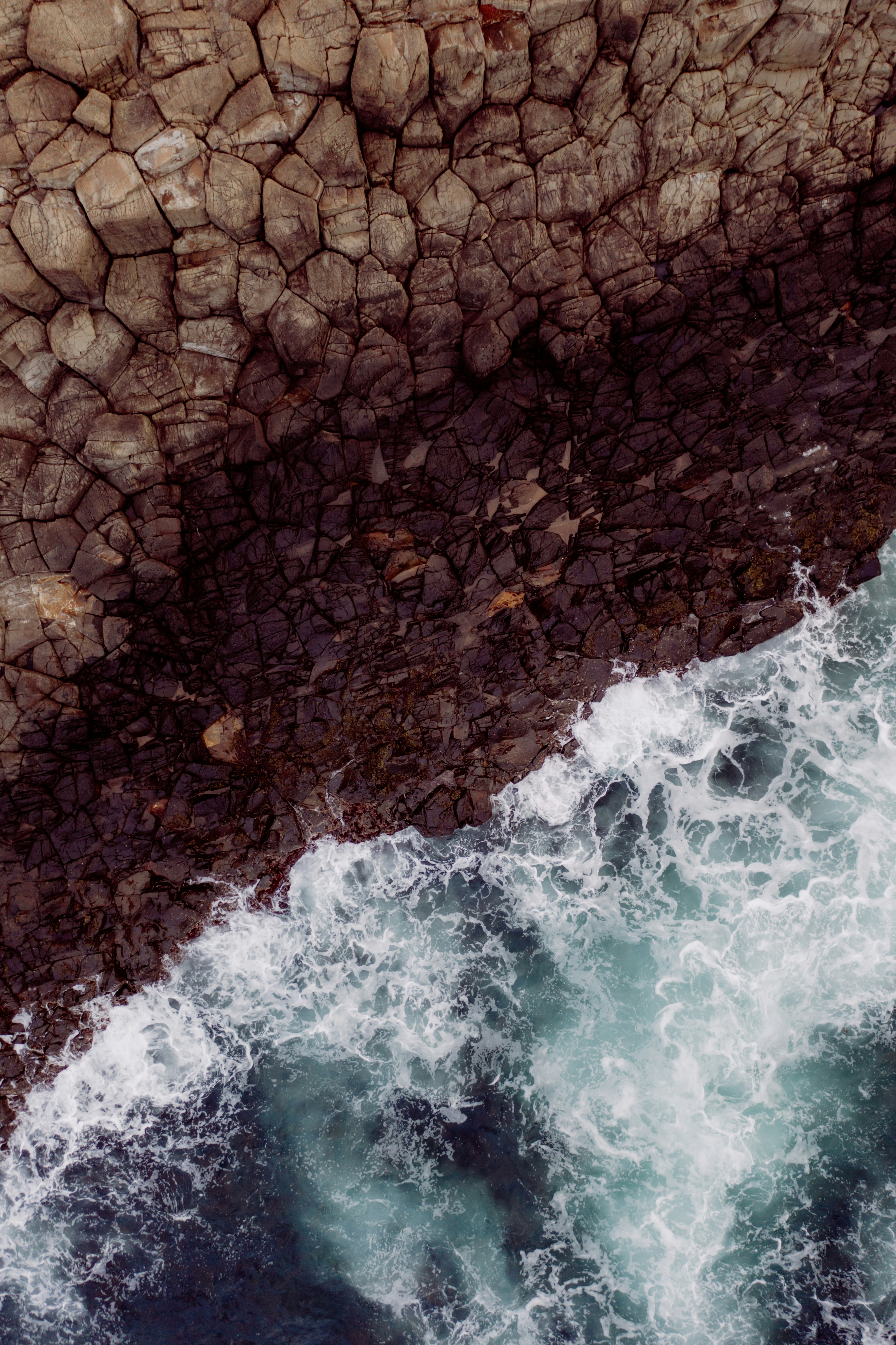 brown and black rocks beside body of water